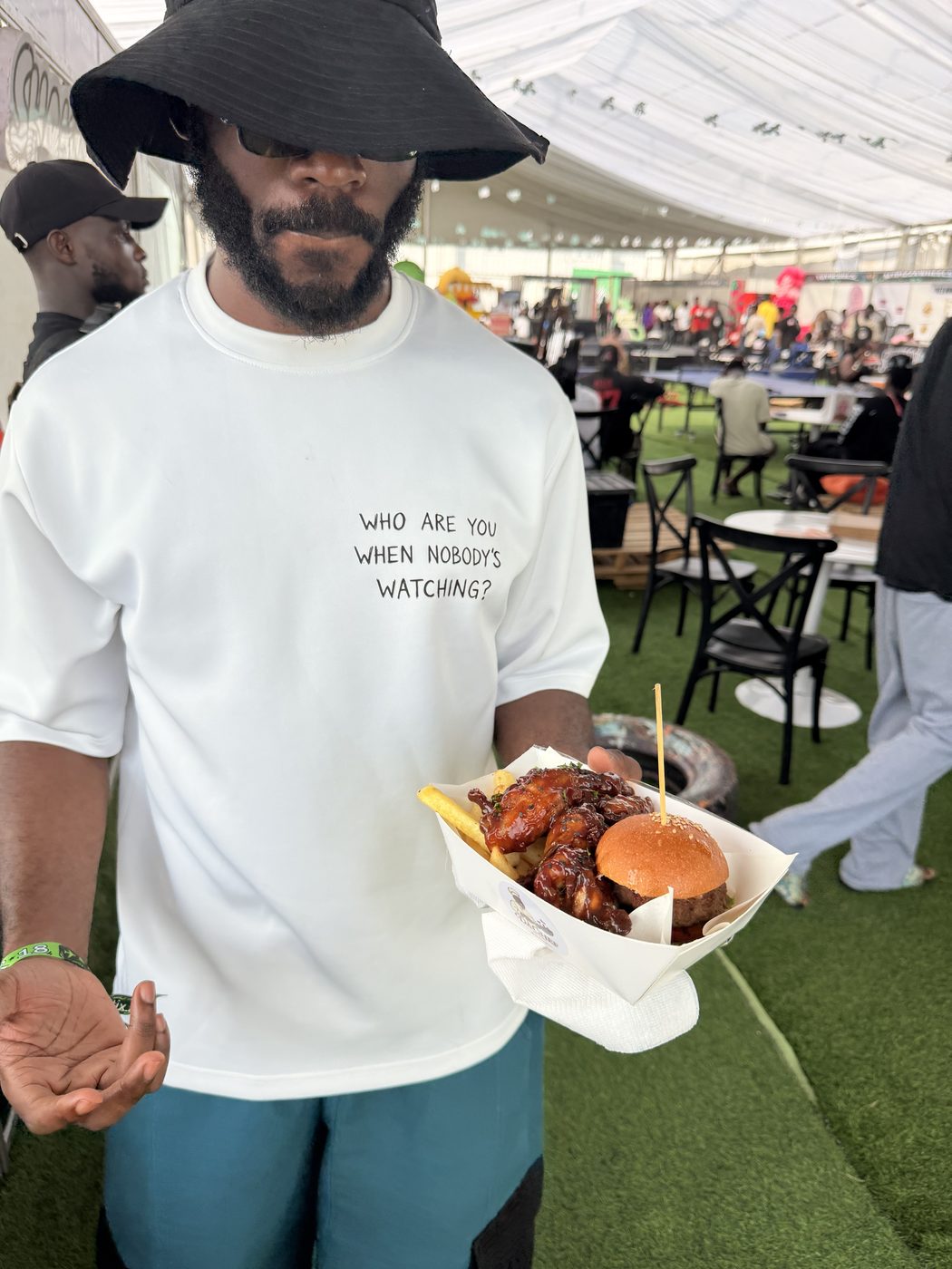 Customer holding DaChef wings and burger at an outdoor pop-up