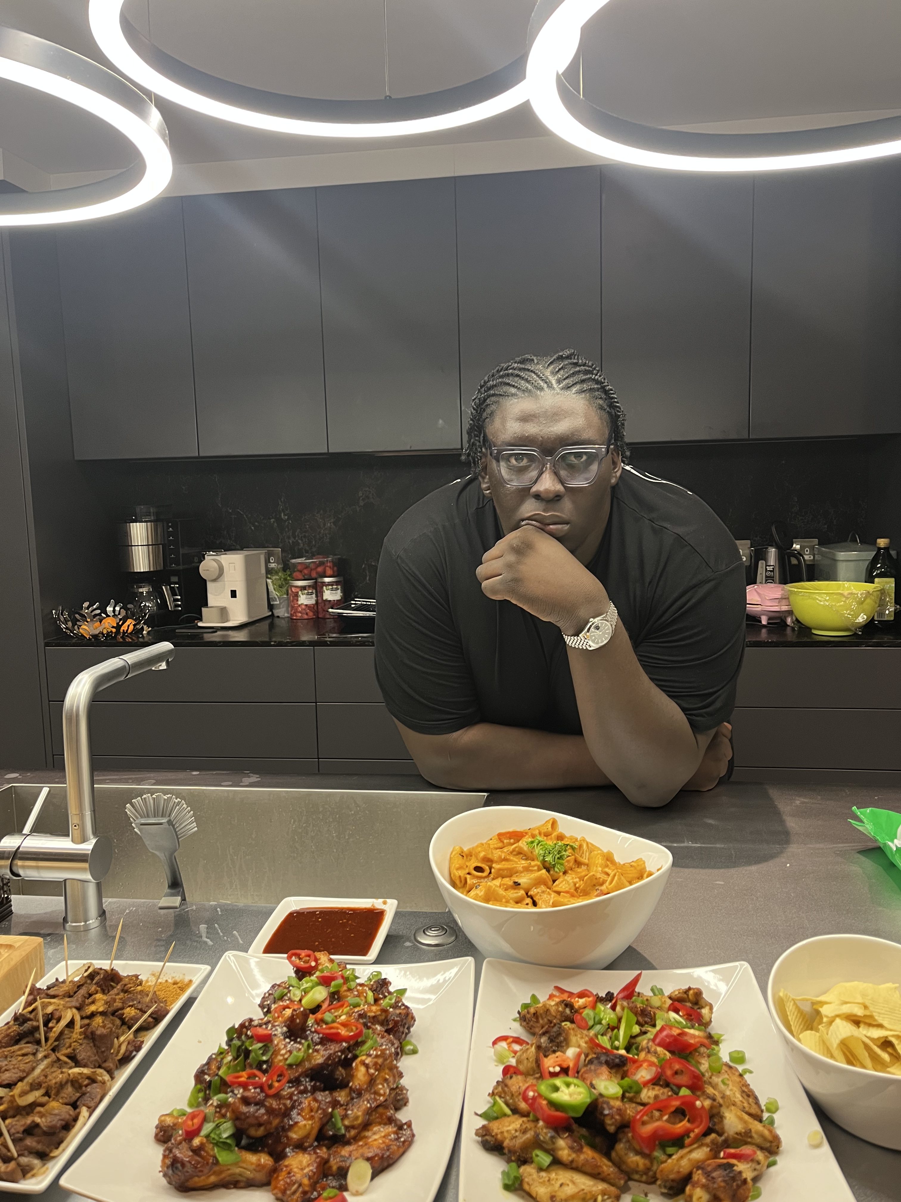 Damilola Atere, Founder of DaChef Kitchens, in the kitchen with food spread before him